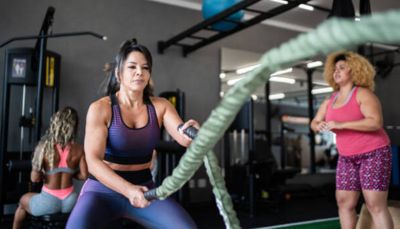 Mature woman working out with battle ropes at the gym